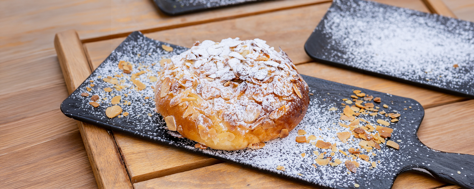 Dolce con mandorle a lamelle e zucchero a velo su un piatto di ardesia nera, pasticceria Bar San Francesco a Palermo